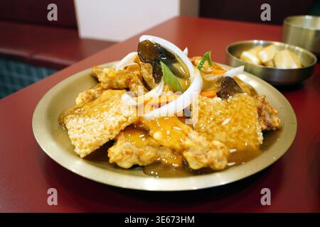 Knuspriges süßes und saures Schweinefleisch mit gebratener Reiskruste (Nurungji Tangsuyuk) in Messingplatte, chinesische Küche im koreanischen Stil Stockfoto