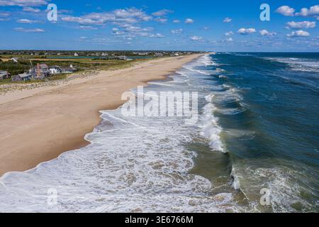 Aus der Vogelperspektive auf die Wellen des Atlantiks, die auf den Sandstrand mit Häusern an der Küste auf Long Island New York Rollen Stockfoto