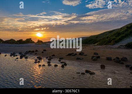 Sonnenuntergang über flachem Wasser und sandiger Küste in Pirates Cove Long Island New York mit Reflexionen und dramatischem Himmel Stockfoto
