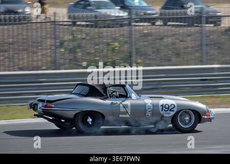 Drama in Runde 1! Der Jaguar E-Type 1961 blockiert seine Räder und hinterlässt eine Rauchwolke im Bremsbereich Stockfoto