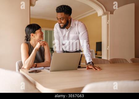 Zwei professionelle Kollegen tauschen Ideen und Planungsstrategien über ein Notebook am Schreibtisch an einem modernen Arbeitsplatz aus Stockfoto