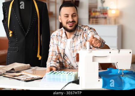 Männlicher Schneider mit Nähmaschine im Atelier Stockfoto