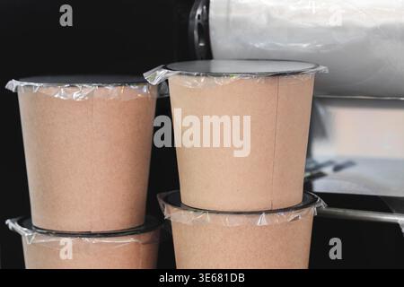 Gestapelte braune Papierbecher mit durchsichtigen Kunststoffdeckeln. Die Cups zeigen eine Struktur und ein praktisches Design. Ideal für Lebensmittelservice, Verpackung oder umweltfreundliches Branding Stockfoto