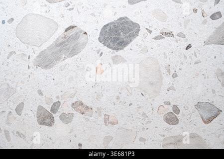 Weiße Terrazzo-Oberfläche mit grauen und beigefarbenen Steinfragmenten. Ideal für Hintergründe oder Texturen in Konstruktionsprojekten. Sauber. Geeignet für Websites, Apps Stockfoto