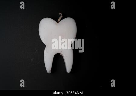 Weiße zahnförmige Kerze mit Docht auf dunkelschwarzem Hintergrund, minimale Zusammensetzung, Ansicht von oben nach unten, isoliertes Objekt Stockfoto