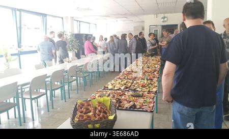 Reihen Fruitfilled Tische Staff Schlange Lunch, Körbe Mit Pfirsichen Und Äpfeln Füllen Lange Serviertische In Der Hellen Cafeteria, Arbeiter Halten Fest Stockfoto