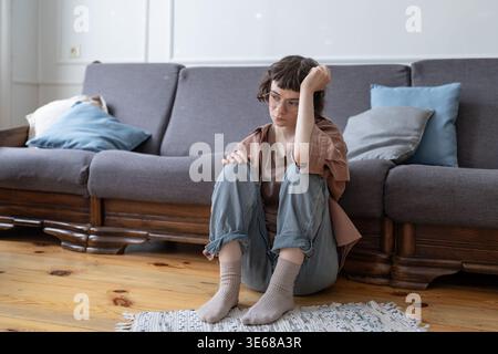 Verärgert einsames Teenager-Mädchen fühlt emotionale Müdigkeit, braucht Unterstützung durch Freundschaft, denkt über Probleme nach. Traurig frustrierter Teenager, der zu Hause auf dem Boden sitzt Stockfoto