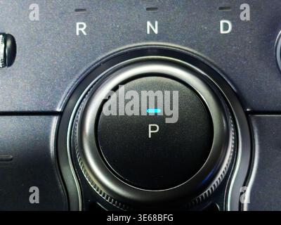 Nahaufnahme eines schlanken Drehschalters in einem modernen Fahrzeuginnenraum. Zeigt P-, R-, N- und D-Positionen mit einer elektronischen Parkanzeige auf einer Textur an Stockfoto