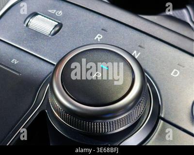 Nahaufnahme eines schlanken Drehschalters in einem modernen Fahrzeuginnenraum. Zeigt P-, R-, N- und D-Positionen mit einer elektronischen Parkanzeige auf einer Textur an Stockfoto