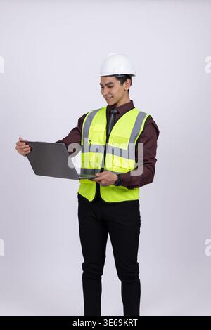 Ingenieur in Sicherheitsweste, der bei der Arbeit einen Laptop hält Stockfoto