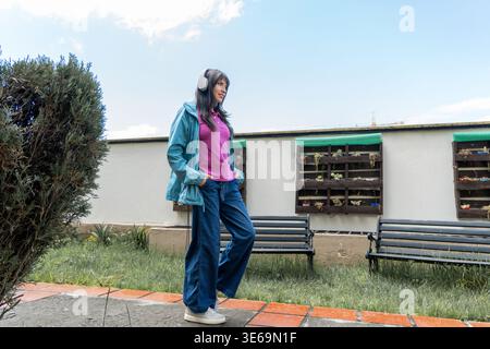 Junge Frau, die an einem sonnigen Tag draußen mit Kopfhörern Musik hört Stockfoto