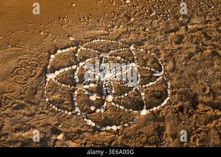 Symbol der Blume des Lebens aus Kieselsteinen am Strand von Agios Gordis. Spirituelles Steinmosaik in Korfu, Griechenland, aufgenommen am 12. Juli 2023. Stockfoto