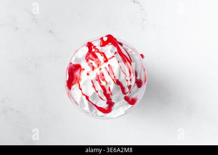 Ein Blick von oben nach unten auf einen Milchshake mit Schlagsahne und Erdbeersirup. Stockfoto