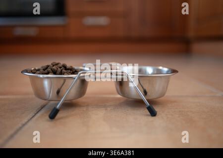 Tierschalen aus Metall mit Trockenfutter auf dem Boden. Konzept der Tierpflege, der Fütterungsroutine und der häuslichen Lebensweise. Stockfoto