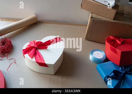 Geschenkboxen mit Bändern und Verpackungsmaterialien am Arbeitsplatz. Konzept des E-Commerce, des Versands kleiner Unternehmen und der Produktvorbereitung. Stockfoto