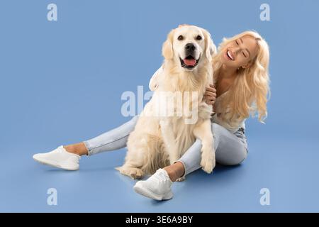 Frau sitzt auf dem Boden mit Golden Retriever Dog und Lächeln Stockfoto