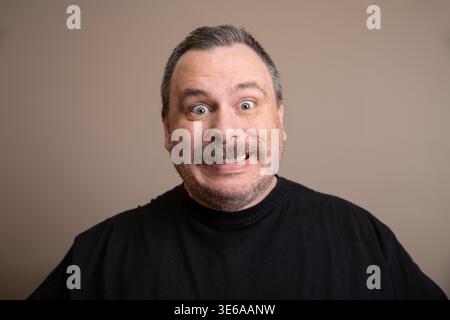 Der Mann sieht überrascht mit fröhlichem Ausdruck aus, ideal für Comedy oder lässige Themen Stockfoto
