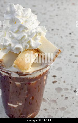 Eine Nahaufnahme einer Tasse geschmolzener Haselnussschokolade, gekrönt mit Käsekuchen-Häppchen. Stockfoto