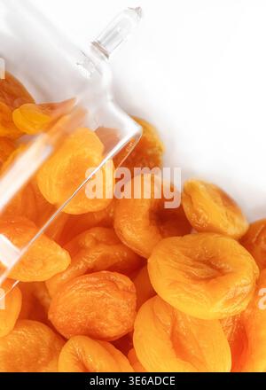 Glasgefäß auf der Seite voll von lebhaften Orangen getrockneten Aprikosen auf weißem Hintergrund Stockfoto