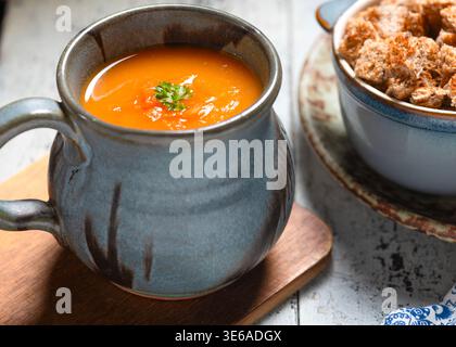 Hausgemachte warme Wintermohrensuppe mit Wurzelgemüse in einer Tasse mit Croutons im Hintergrund mit Kopierraum Stockfoto