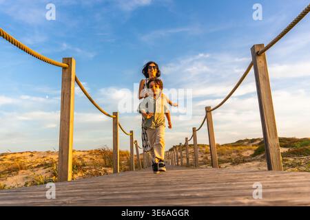 Mutter und Sohn laufen während des Urlaubs auf der Strandpromenade Stockfoto
