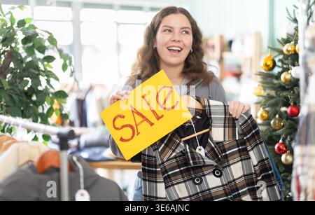 Junge Frau mit Verkaufsschild im Bekleidungsgeschäft Stockfoto