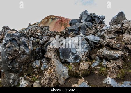 Obsidianfelsen in Laugahraun mit dem Rhyolithberg Brennisteinsalda in Landmannalaugar, Island Stockfoto