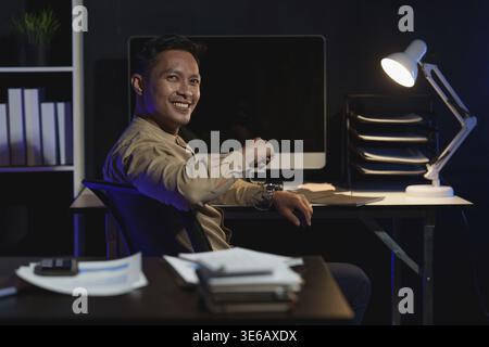 Asiatischer Geschäftsmann, der über die Zeit in der Nacht arbeitet. Geschäftskonto- und Finanzierungskonzept Stockfoto