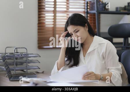 Junge Geschäftsfrau, die im Büro arbeitet und Kopfschmerzen hat Stockfoto