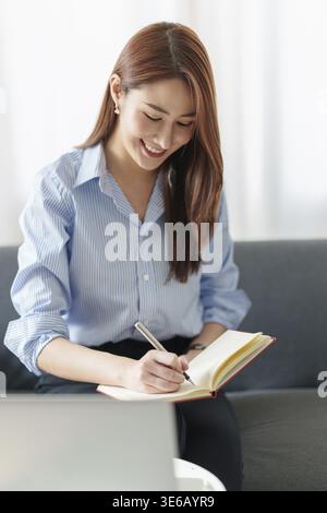 Schöne asiatische Geschäftsfrau, die sich ein lehrreiches Webinar auf Laptop ansieht. Finanzierungskonzept Stockfoto