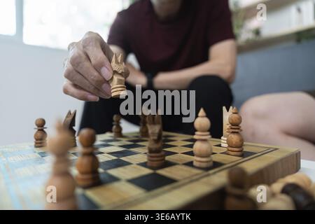 Zwei Personen spielen Schach und konzentrieren sich auf Strategie und Konzentration in einem gemütlichen Innenbereich Stockfoto
