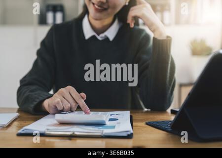 Asiatische Geschäftsfrau, die Präsentation oder wichtige E-Mail von Finanzdaten vorbereiten. Wirtschaftsprüfer, der im Home Office arbeitet Stockfoto