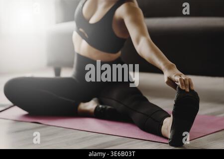 Junge Frau, die Yoga praktiziert, folgt der Lehrerin zu Hause. Konzept der Ruhe und Entspannung Stockfoto