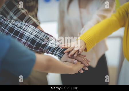 Eine Gruppe multirassischer Menschen, die ihre Hände zusammen legen und das Einseins-Symbol zeigen Stockfoto