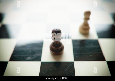 Nahaufnahme hölzerner Schachfiguren auf einem Brett, die ein stehendes Duell, ein gefallenes Paar und eine chaotische Endspielszene zeigen. Horizontale Studioaufnahme im Innenbereich. Stockfoto