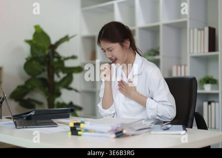 Eine junge Frau drückt ihre Emotionen aus, während sie an ihrem Schreibtisch sitzt und die Herausforderungen zeigt, die es mit dem Umgang mit Stress in einem beruflichen Umfeld zu tun hat Stockfoto