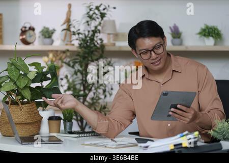 Ein Mann, der sich in einem eleganten Büro mit einem Tablet auseinandersetzt und die Rolle der Technologie für moderne Kommunikation und Produktivität betont Stockfoto