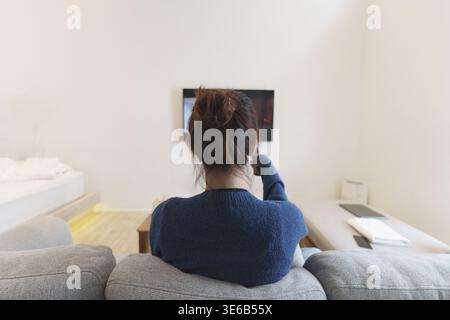 Aufgeregt, glücklich moderne Frau beobachten WM Fußballspiel, Meisterschaft auf der Couch zu Hause. Sport, Fernsehen, Spaß haben Stockfoto