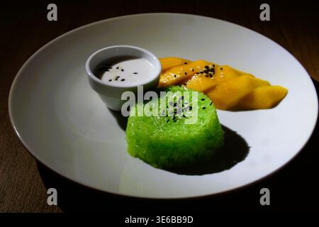 Nahaufnahme des klassischen thailändischen Manggo Sticky Rice, ein beliebtes thailändisches Dessert mit süßem Kokos-Kleberreis, frischer reifer Manggo-Scheibe und schwarzem Sesam. Stockfoto