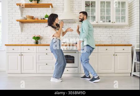 Glückliches sorgloses Paar, das zusammen in der modernen Küche zu Hause tanzt und lächelt Stockfoto