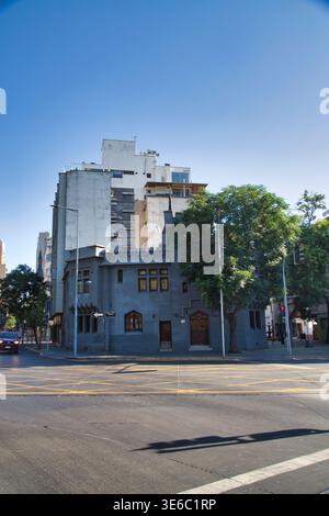 Blick auf Ein kleines historisches Gebäude mit Bäumen und höheren modernen Gebäuden dahinter in Santiago de Chile. Stockfoto