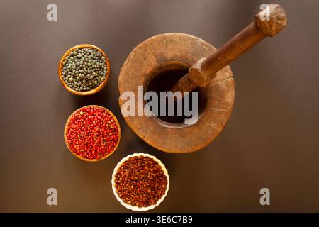 Samen, die zum Mahlen im Mörtel vorbereitet werden. (Pistacia terebinthus) Rote Pfefferkerne und Sumakkerne. Stockfoto