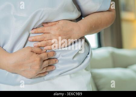 Zugeschnittenes Bild ältere ungesunde Frau, die den Bauch umschließt und an starken Magenschmerzen leidet. Unglückliche Dame mittleren Alters, die sich im Bauch unwohl fühlt. Schließen Stockfoto