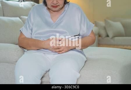 Ältere Frau leidet unter starken Magenschmerzen und Verdauungsstörungen, hält ihren Bauch, repräsentiert Konzepte von Gesundheitsproblemen, chronischen Krankheiten, Disco Stockfoto