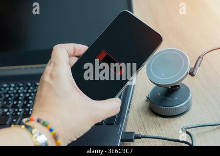 Frau lädt Mobiltelefon mit schnurlosem Schnellladegerät auf dem Desktop auf. Moderne Technologie, tragbares Schnellladekonzept. Stockfoto
