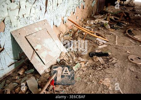 Ukraine, Pripyat, Tschernobyl-Ausschlusszone: Chaotische Anhäufungen von staubigen alten sowjetischen Lehrbüchern und Kinderbüchern auf Schreibtischen und auf dem Boden in heruntergekommenen elementaren en en Stockfoto