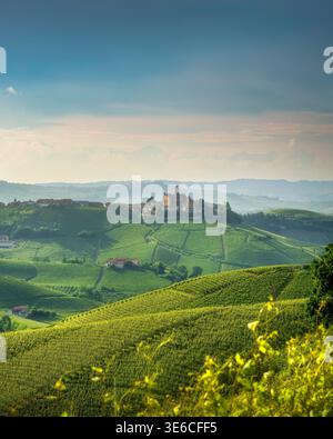 Vertikaler Blick auf die sanften Langhe-Hügel, die von Weinterrassen bedeckt sind, mit dem historischen Dorf und der Burg Castiglione Falletto, Piemont, Italien Stockfoto