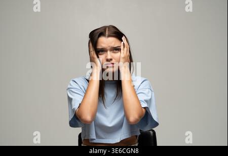 Junge Frau, die Ohren bedeckt, Stress, Angst, Anspannung, Kopfschmerzen oder psychische Probleme erlebt Stockfoto