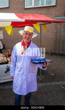 Freundlicher Niederländischer Käsehersteller, Der Proben Am Straßenmarkt Im Freien Im Traditionellen Weißen Mantel Anbietet Stockfoto