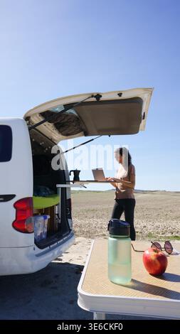 Frau, die einen Laptop an einem tragbaren Schreibtisch im Wohnmobil benutzt, während sie vom Netz fernbleibt Stockfoto